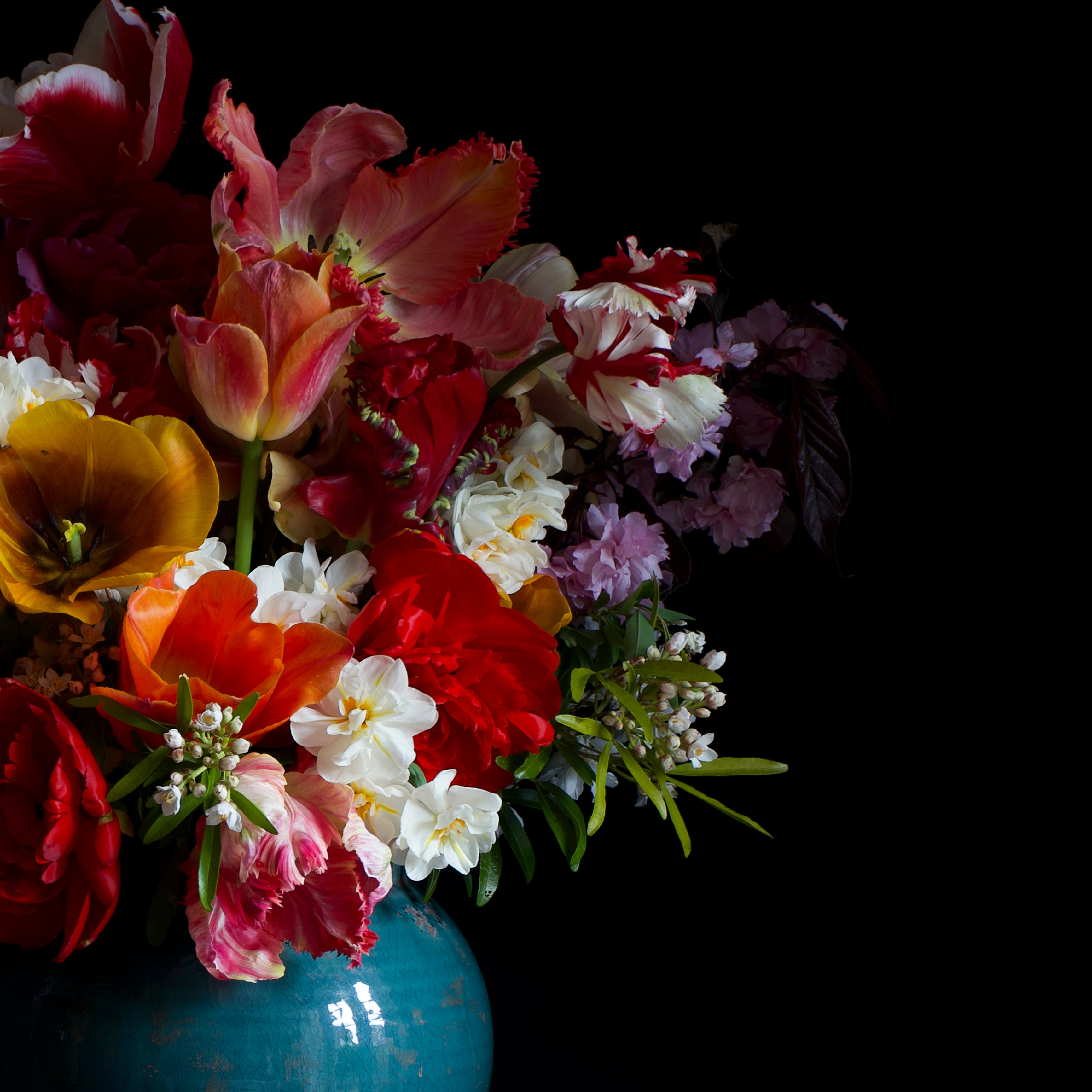 Colorful bouquet of flowers in a blue vase against a black background